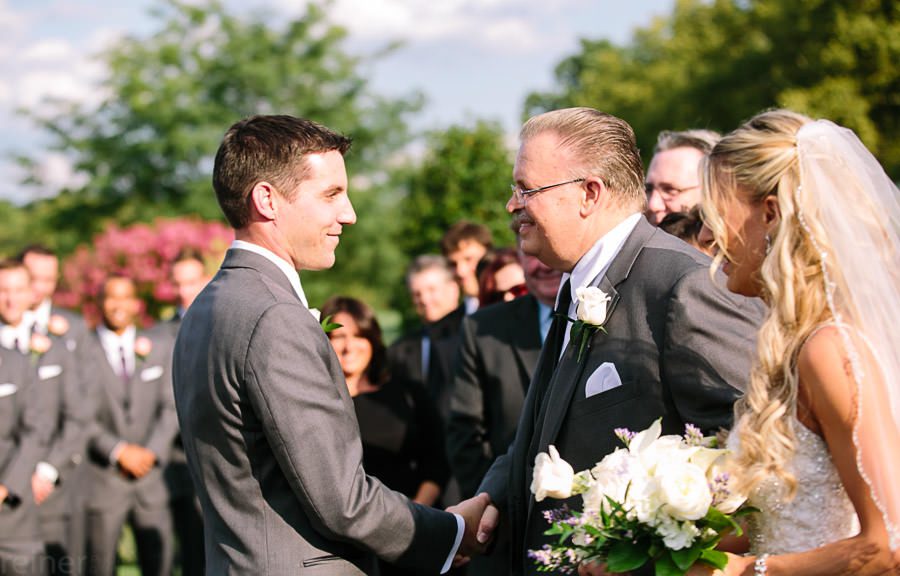 dad shakes grooms hand before wedding ceremony