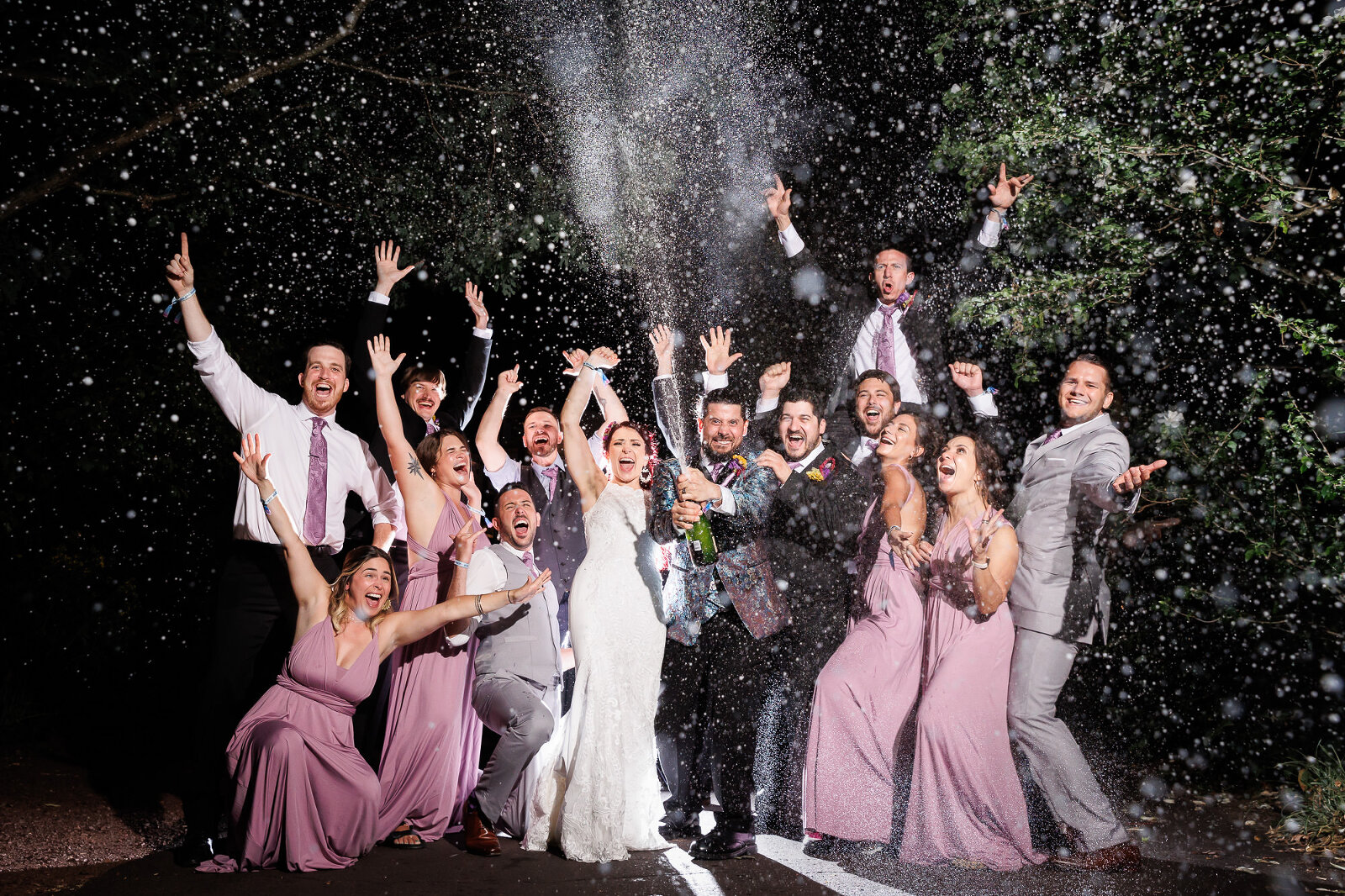 bridal party spraying champaign and having a great time outside of the wedding reception